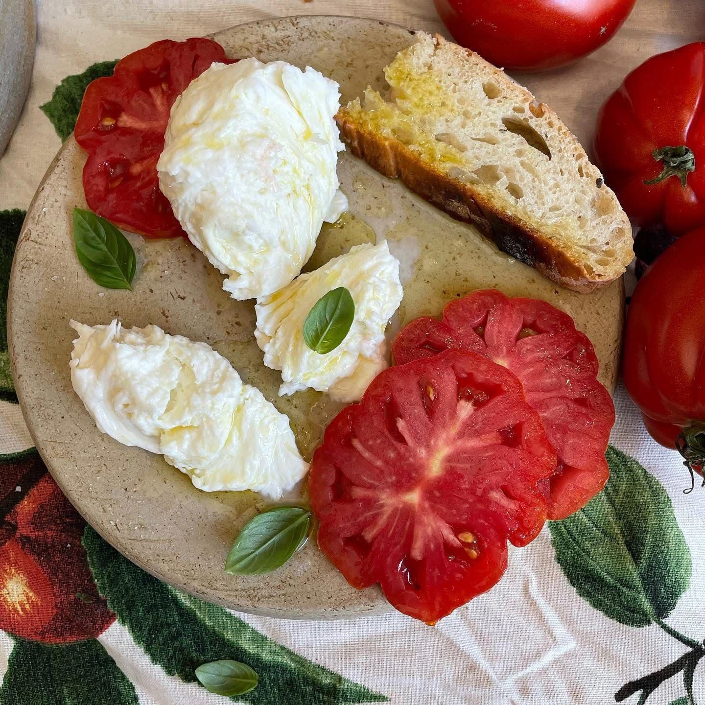 Fresh caprese with full ball of fior di latte, sliced tomatoes, and basil on a rustic plate