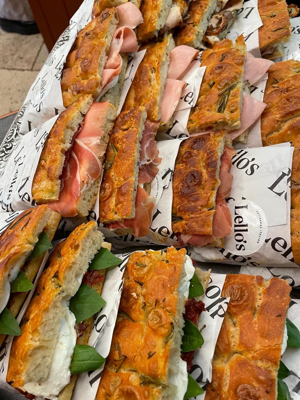 Rows of Lello's focaccia panini with prosciutto and mozzarella in branded wrapping paper