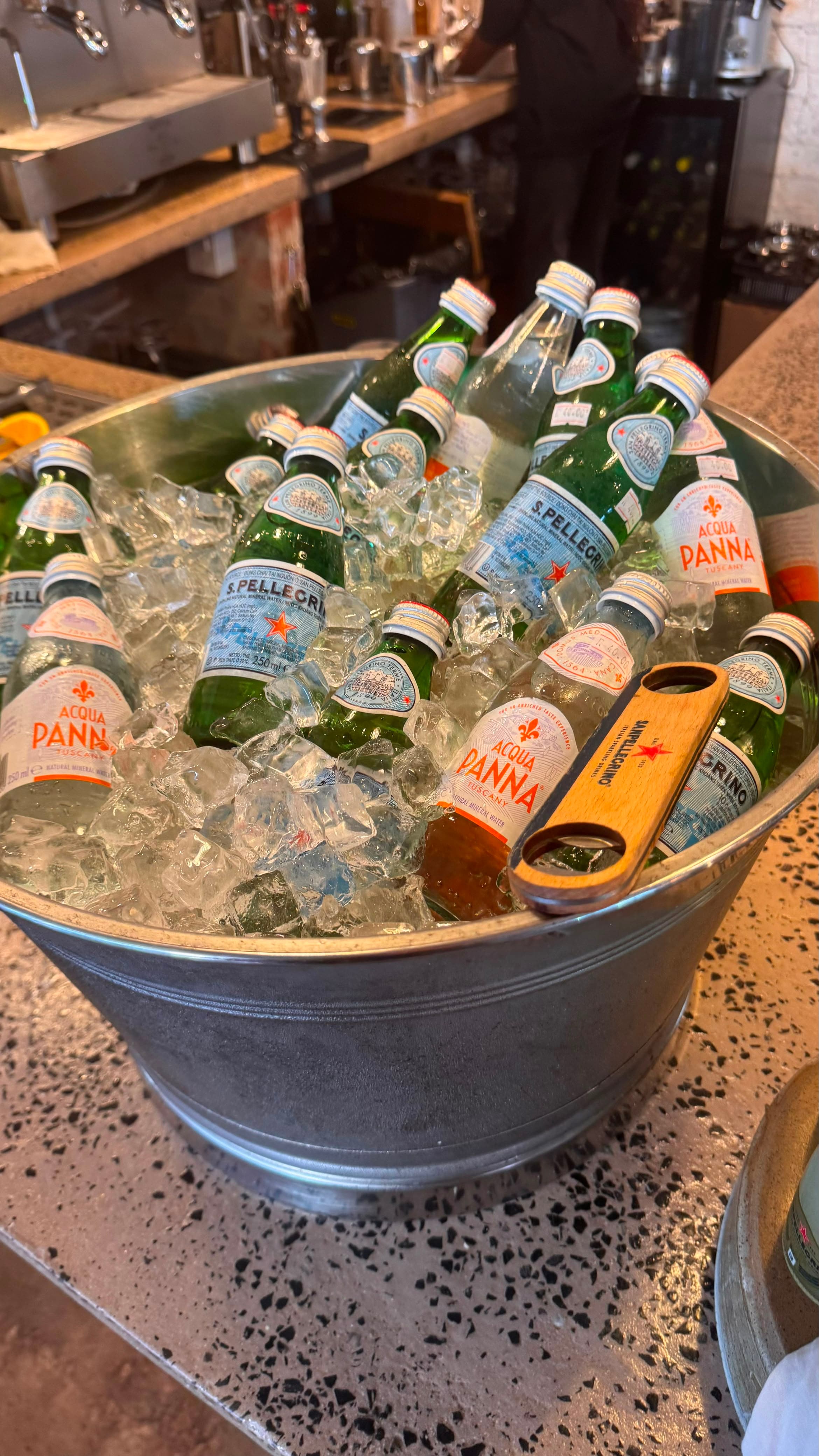 Galvanised bucket filled with ice, San Pellegrino and Acqua Panna bottles on the counter