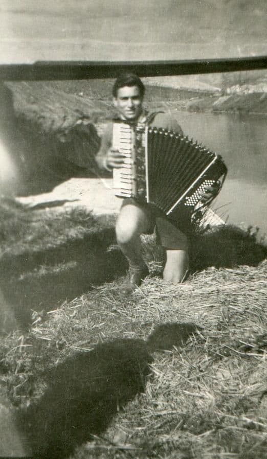 Young Nonno Lello playing the accordion by a river in Italy